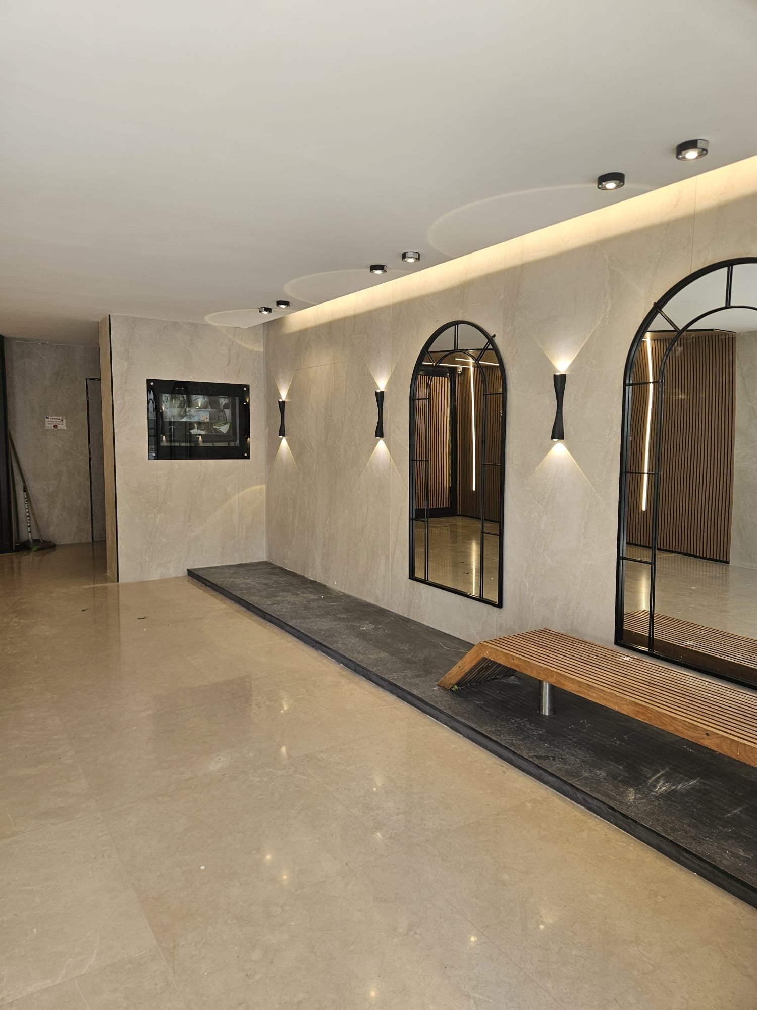 לובי יוקרתי משופץ עם חיפוי שיש, מראות קשת ותאורה נסתרת